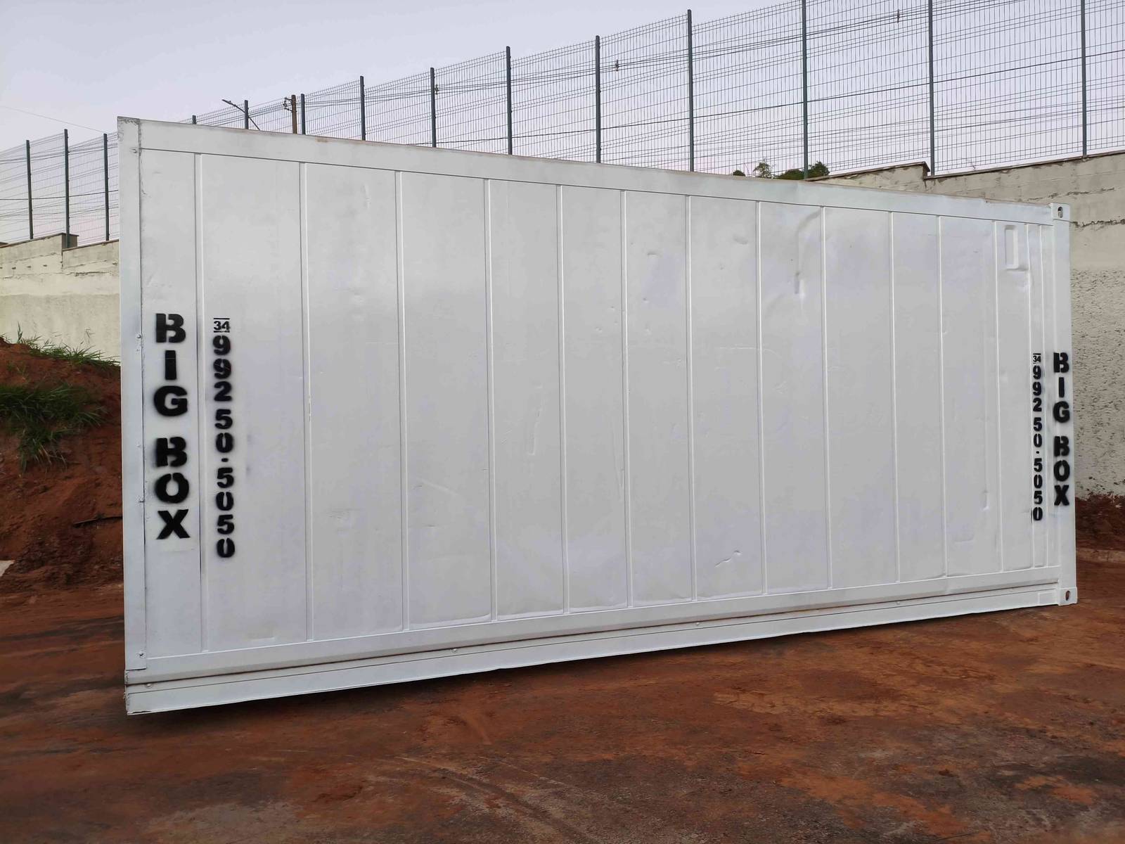 Lateral do container escritório climatizado posicionado sobre terreno de terra em obra de Uberlândia