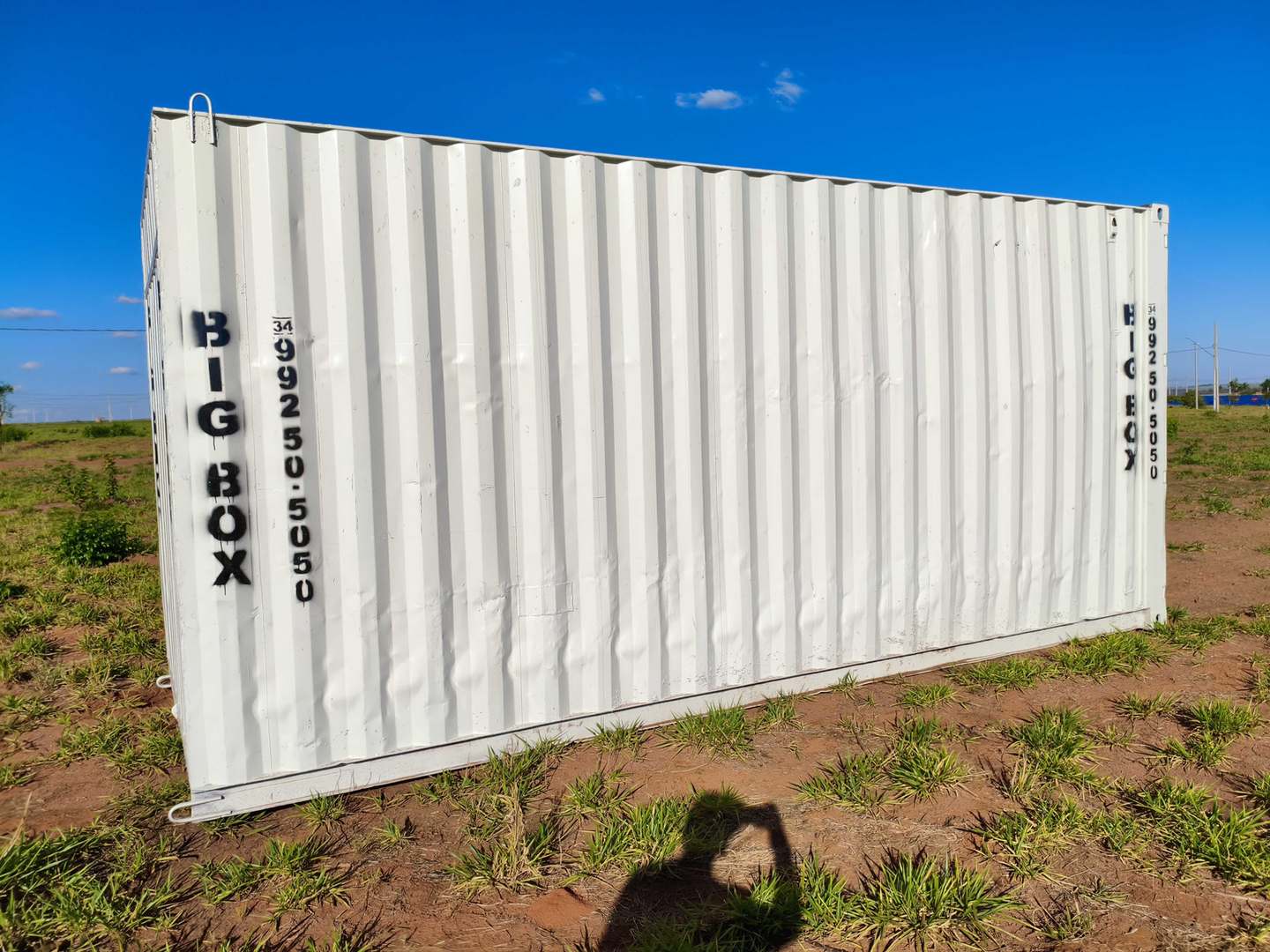 Lateral do container depósito sobre terreno com vegetação baixa