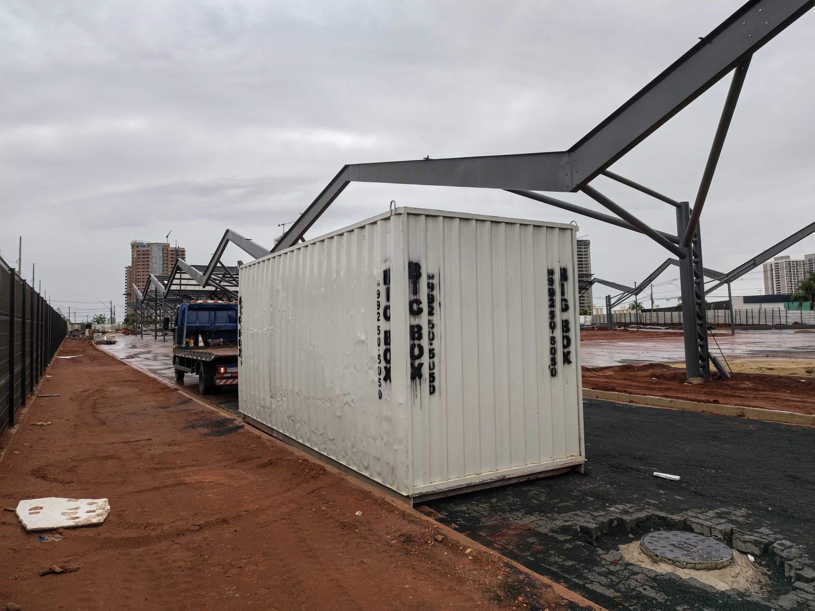 Container estande posicionado na área, com estrutura metálica de cobertura ao lado