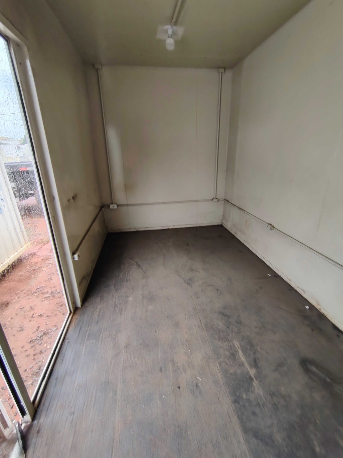 Interior do container estande com porta de vidro e piso escuro