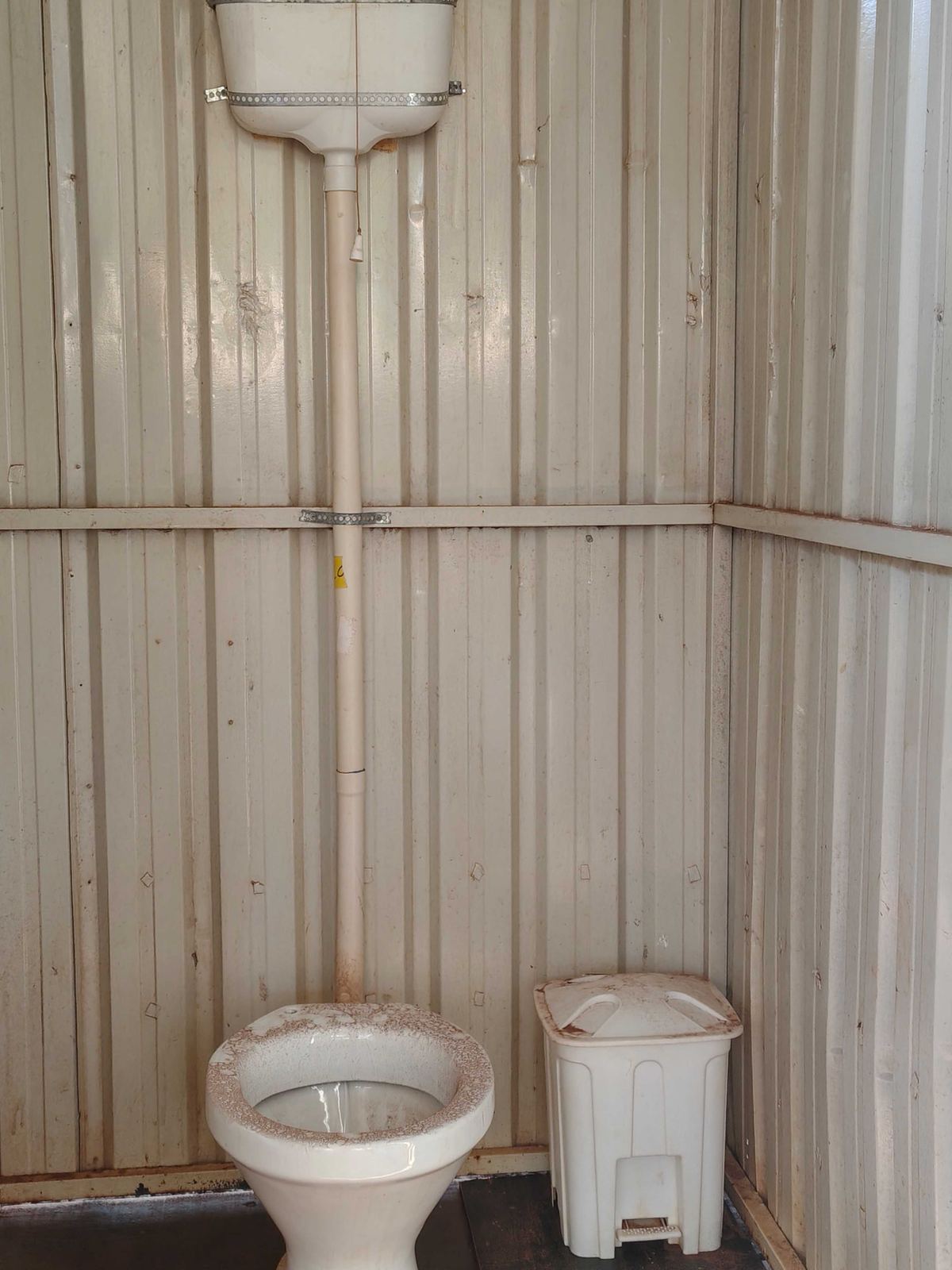 Interior do container sanitário com vaso, caixa de descarga e lixeira