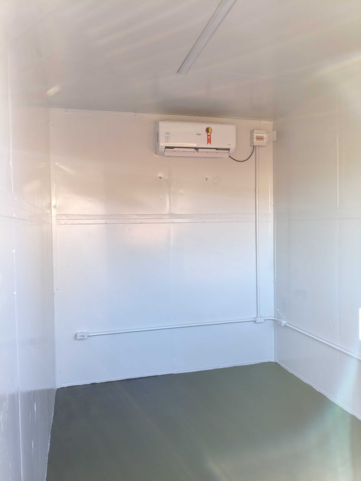 Interior do container escritório compacto com ar-condicionado e piso cinza