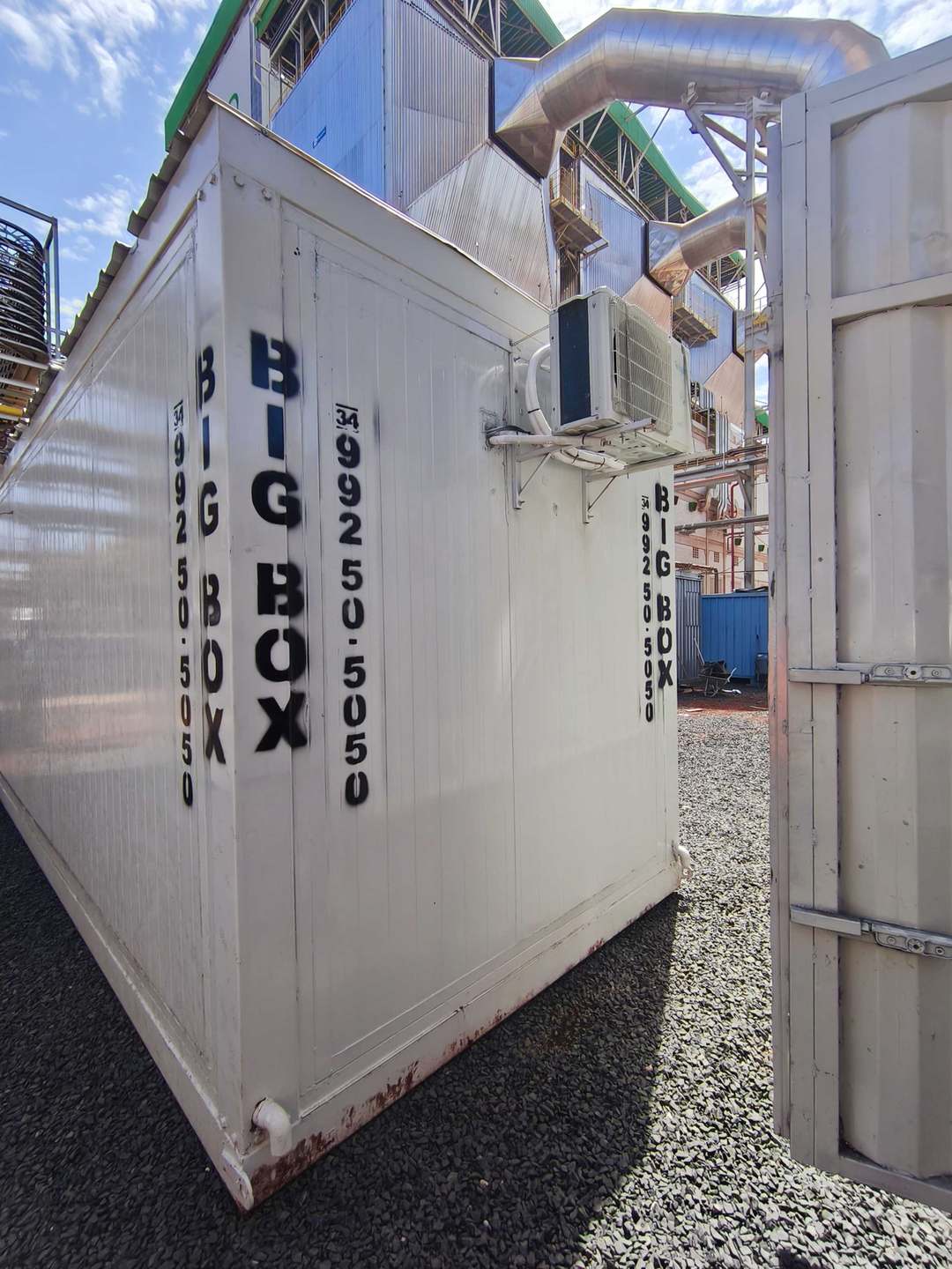 Container escritório com ar-condicionado ao lado de tubulações de planta industrial