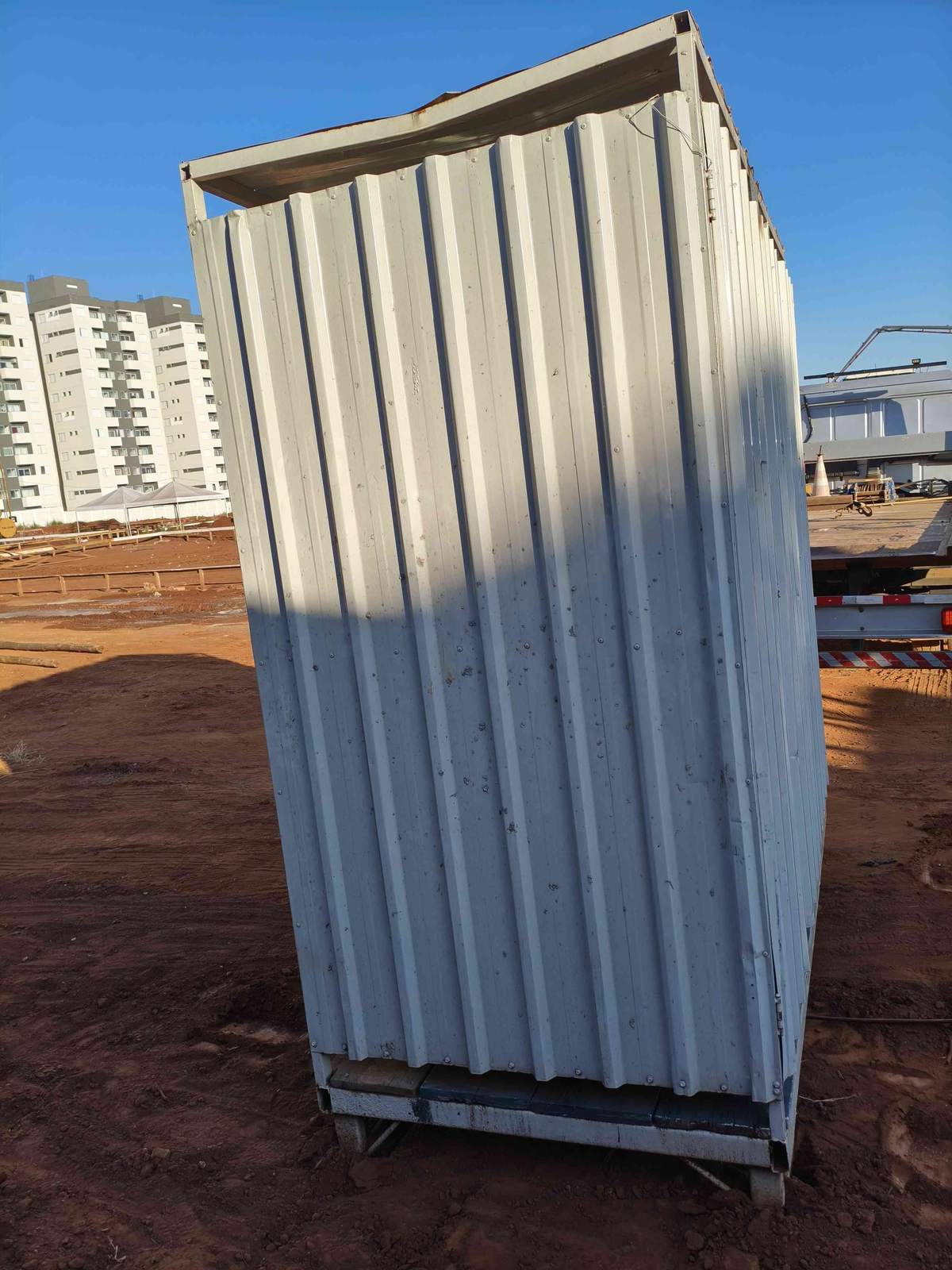 Container banheiro instalado no canteiro com prédios residenciais ao fundo